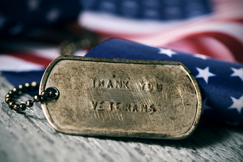 thank you veterans stamped on a dog tag with an american flag background