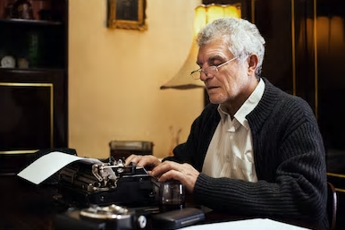 elderly man typing into a typewriter in his office