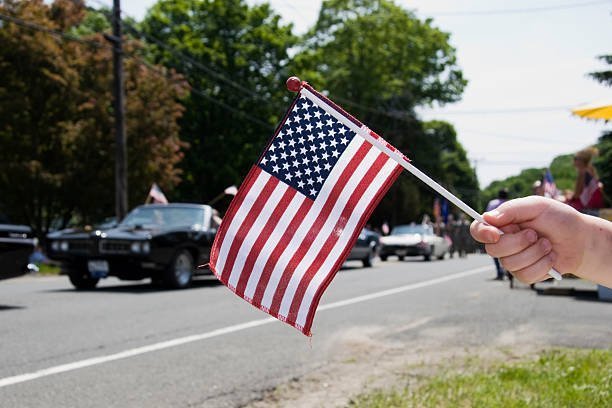 An American Flag in front of a memorial day parade. 