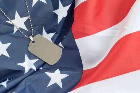 An American Flag with a dog tag laid on top