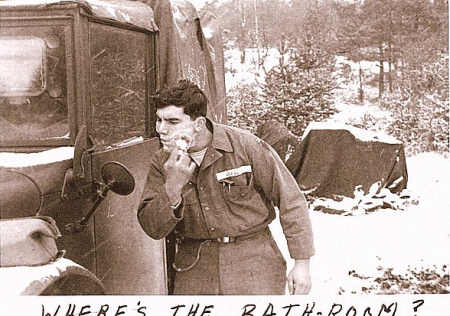 A soldier during the Korean War shaving while using a truck mirror in the snow